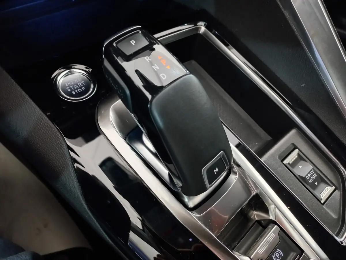Gros plan sur la commande de boîte automatique noire et bouton start/stop du Peugeot 5008 gris foncé, intérieur moderne.