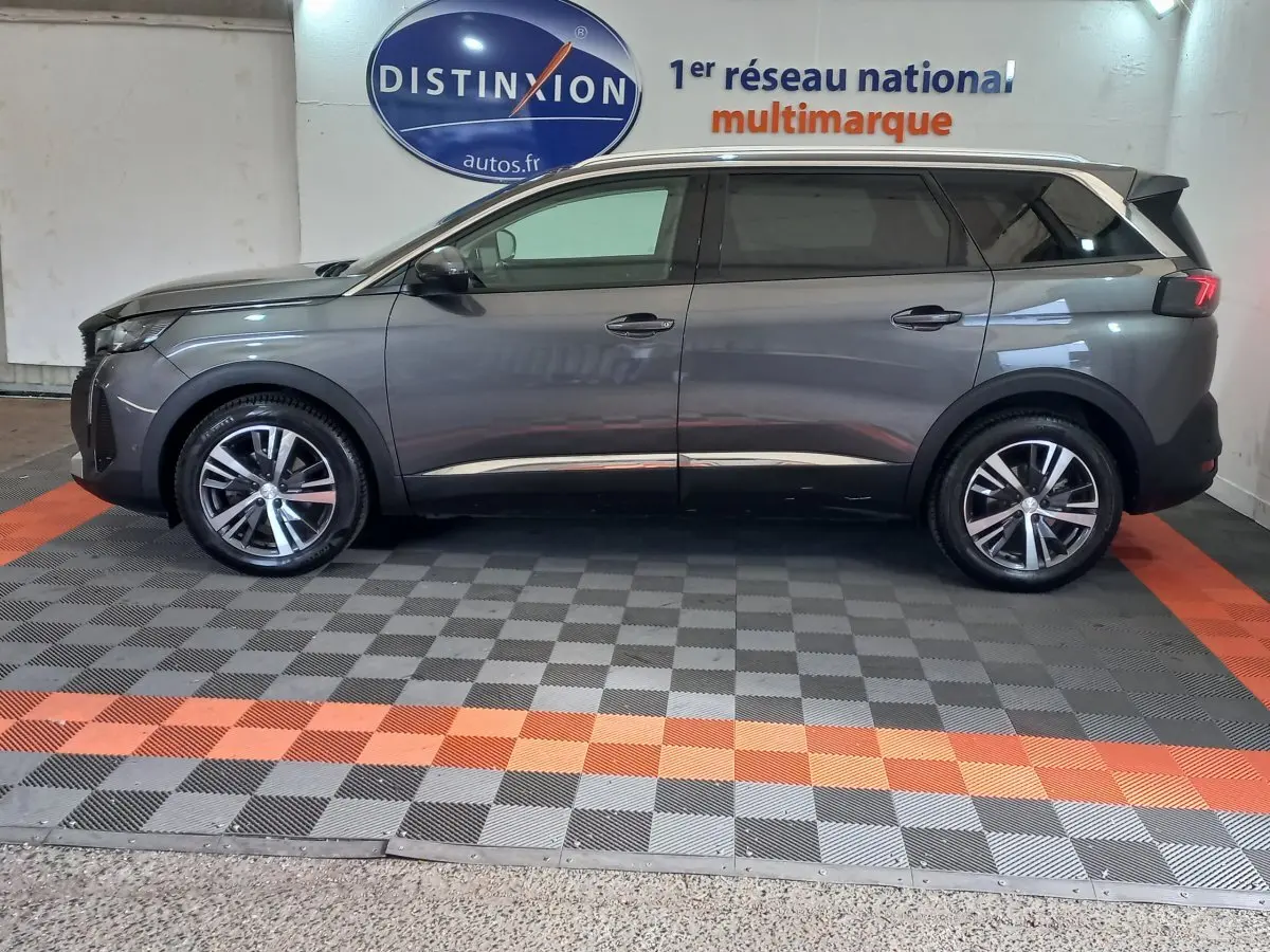 Profil côté gauche d'un Peugeot 5008 gris foncé 2021, finition Allure Pack, dans un showroom multimarque.