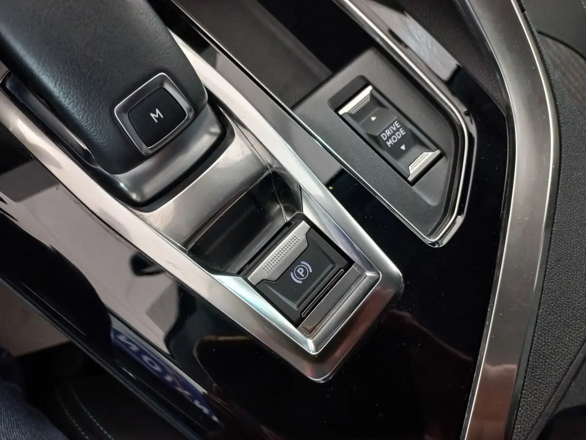 Gros plan sur la console centrale noire du Peugeot 5008 2021, avec bouton frein électrique et sélecteur Drive Mode.
