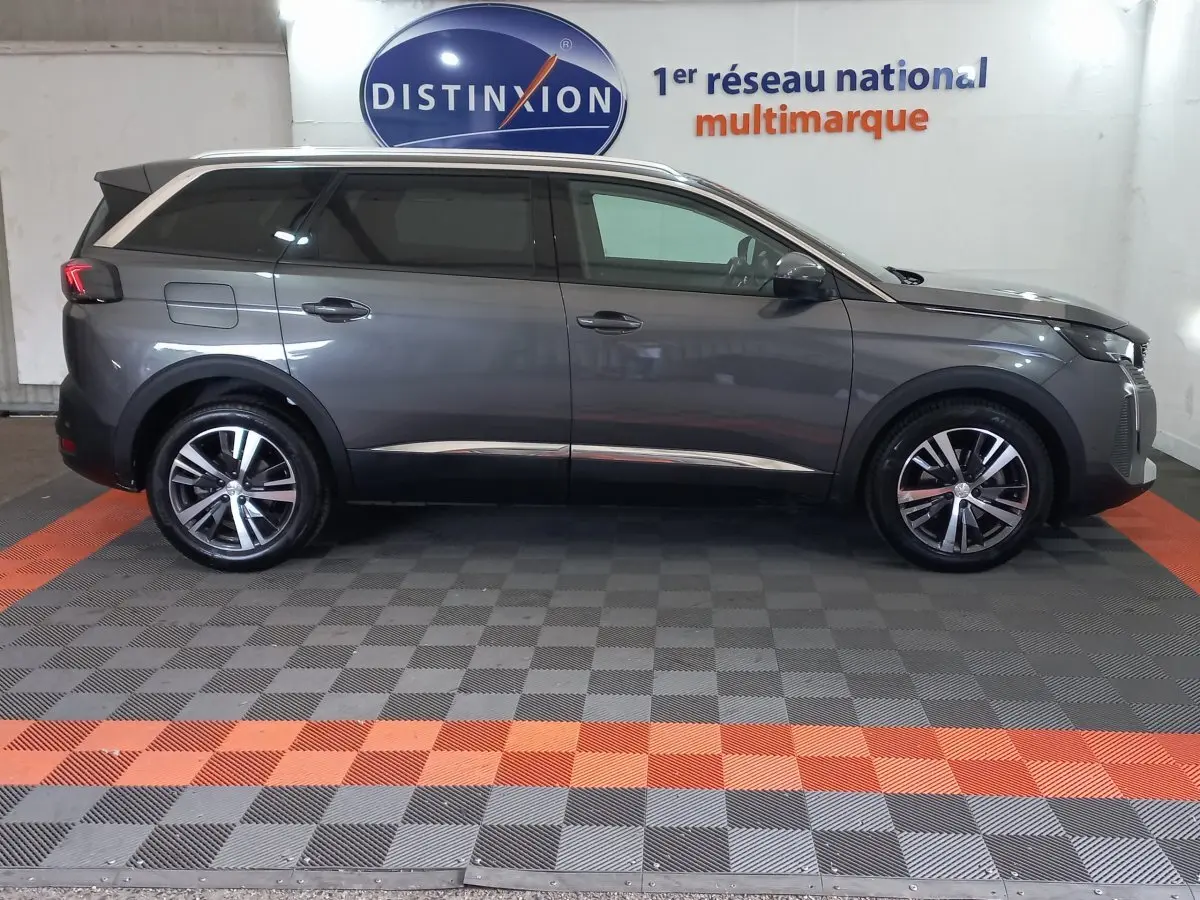 Profil droit d'un Peugeot 5008 gris foncé 2021 garé en intérieur, avec jantes alliage et vitres teintées.