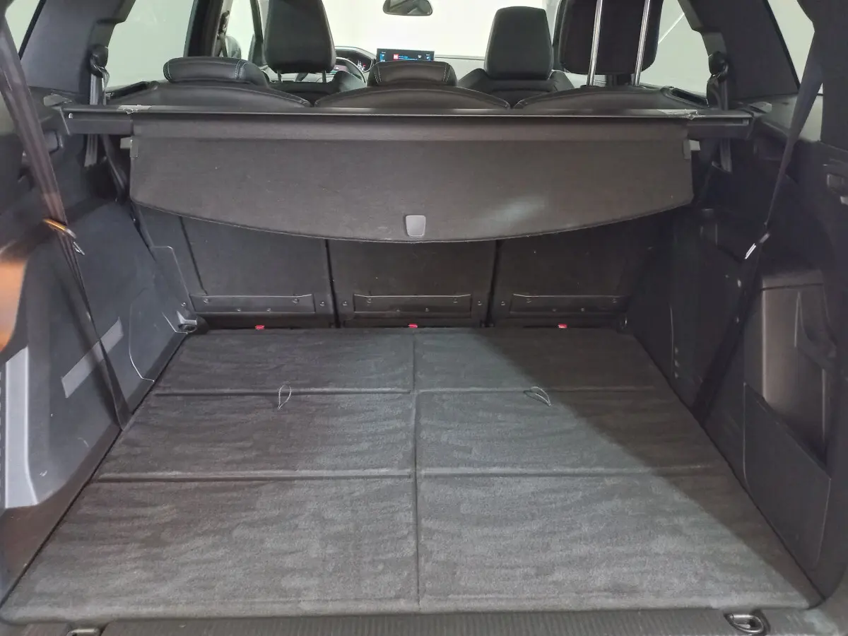Coffre spacieux du Peugeot 5008 gris foncé vu de l'arrière avec plancher plat et banquettes arrière rabattues.