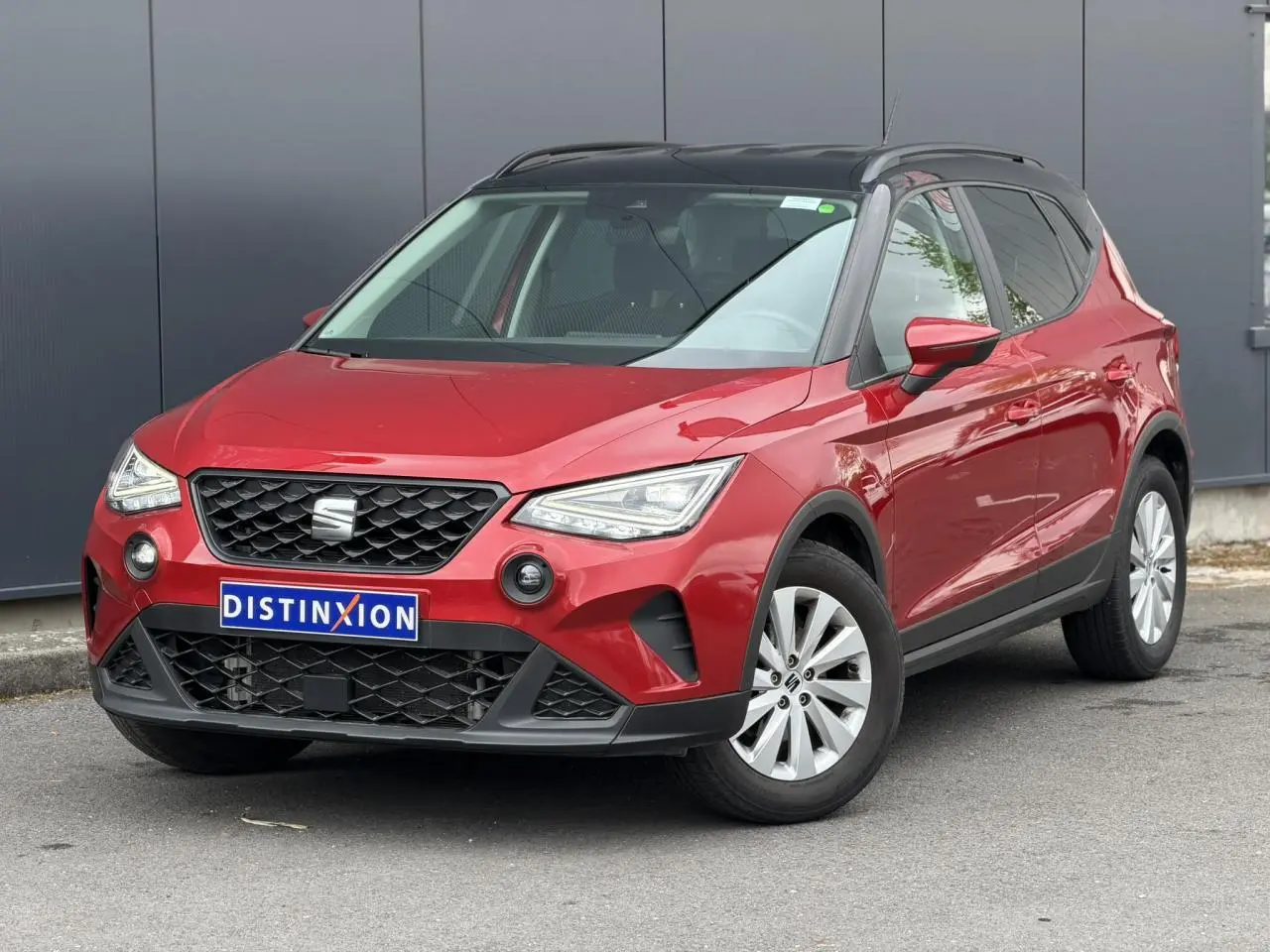 SEAT Arona TSI 115 Style rouge Désir avec toit noir, vue 3/4 avant mettant en valeur la calandre et les phares LED.
