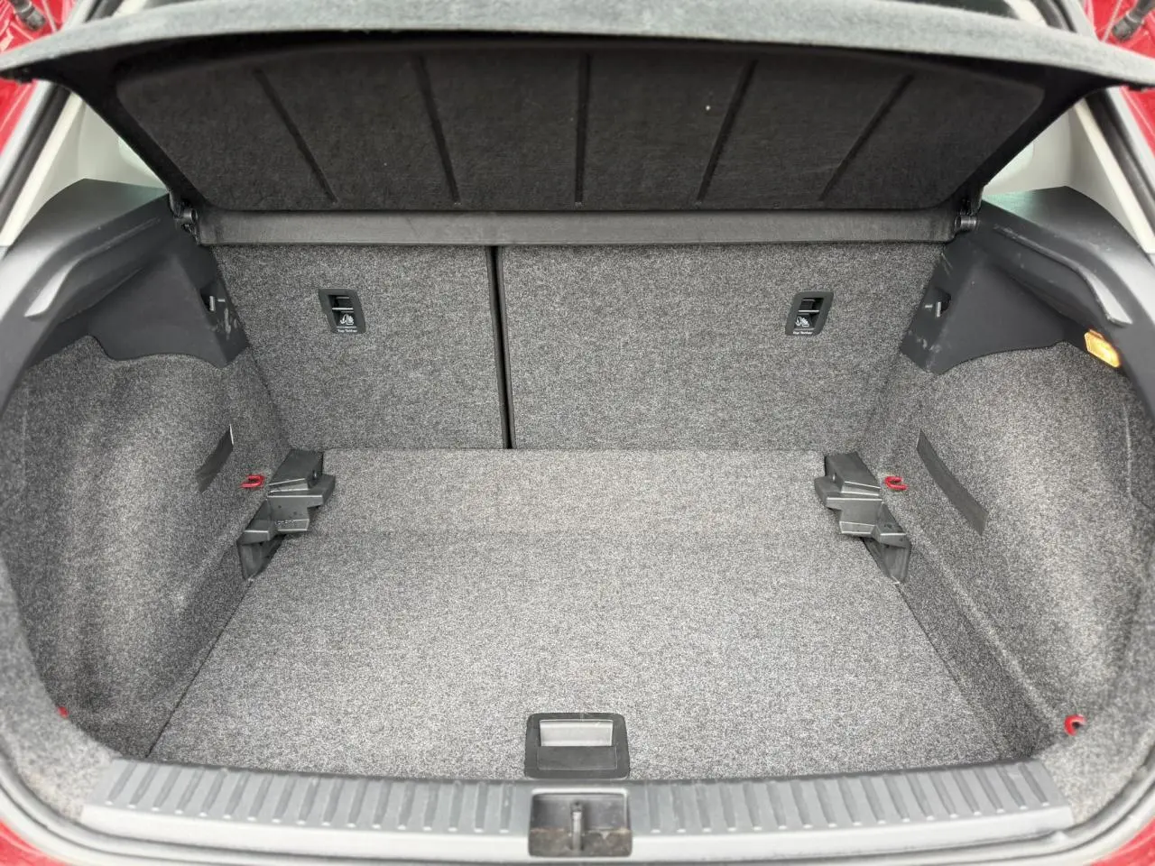 Vue intérieure du coffre spacieux et tapissé de moquette grise du SEAT Arona Rouge Désir, avec la plage arrière relevée.