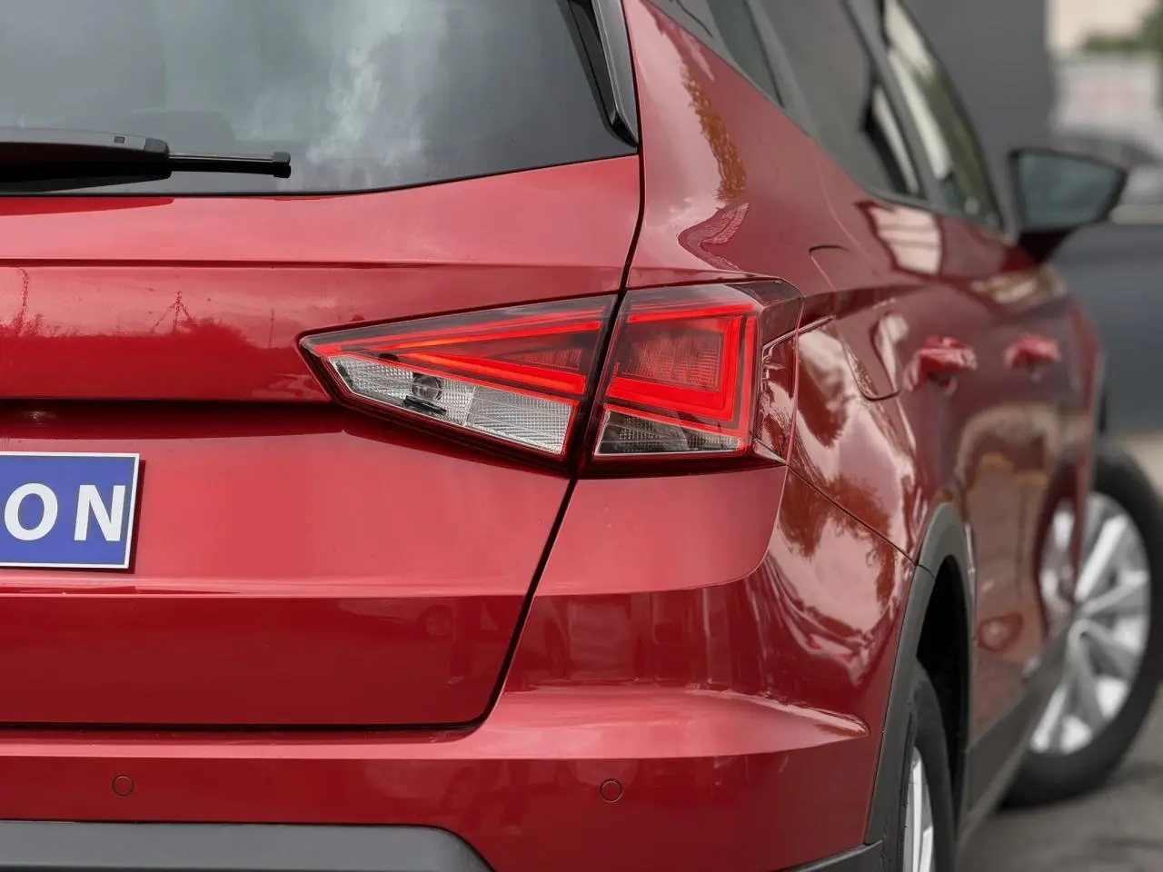 Vue arrière droite d’un SEAT Arona rouge Désir avec feux arrière LED et jantes alliage visibles.
