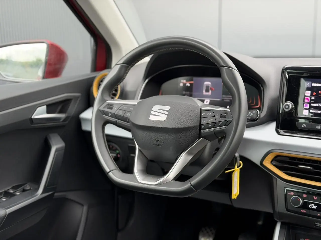 Vue intérieure centrée sur le volant du SEAT Arona 2025, avec détails du tableau de bord et touches multifonctions.