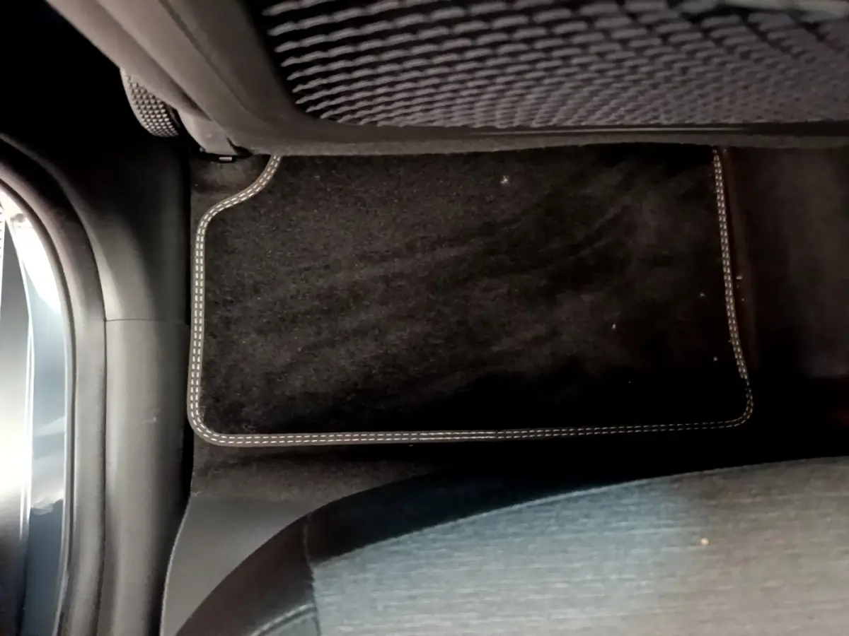 Vue intérieure du plancher côté passager avant avec tapis noir sur Hyundai Kona électrique bleu 2023.