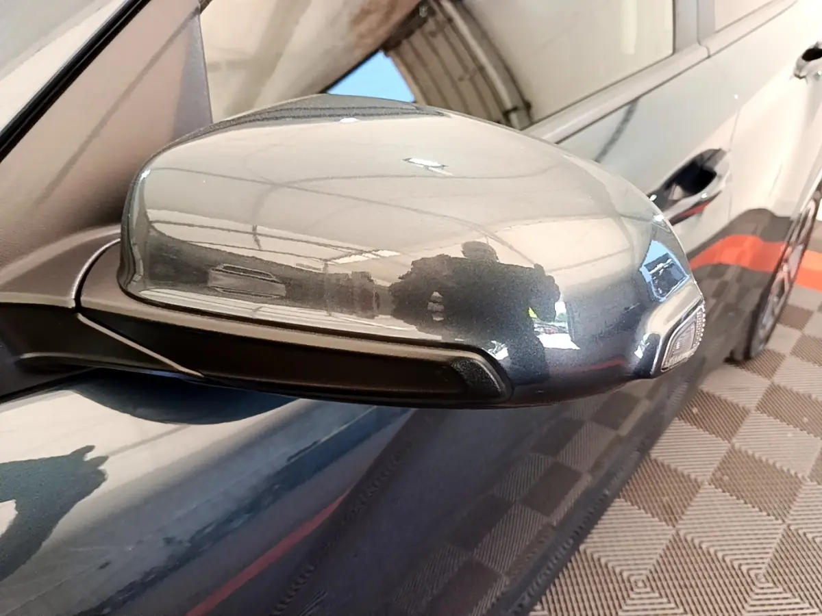 Rétroviseur droit bleu métallisé du Hyundai Kona électrique 2023 avec clignotant intégré, vue rapprochée en extérieur.
