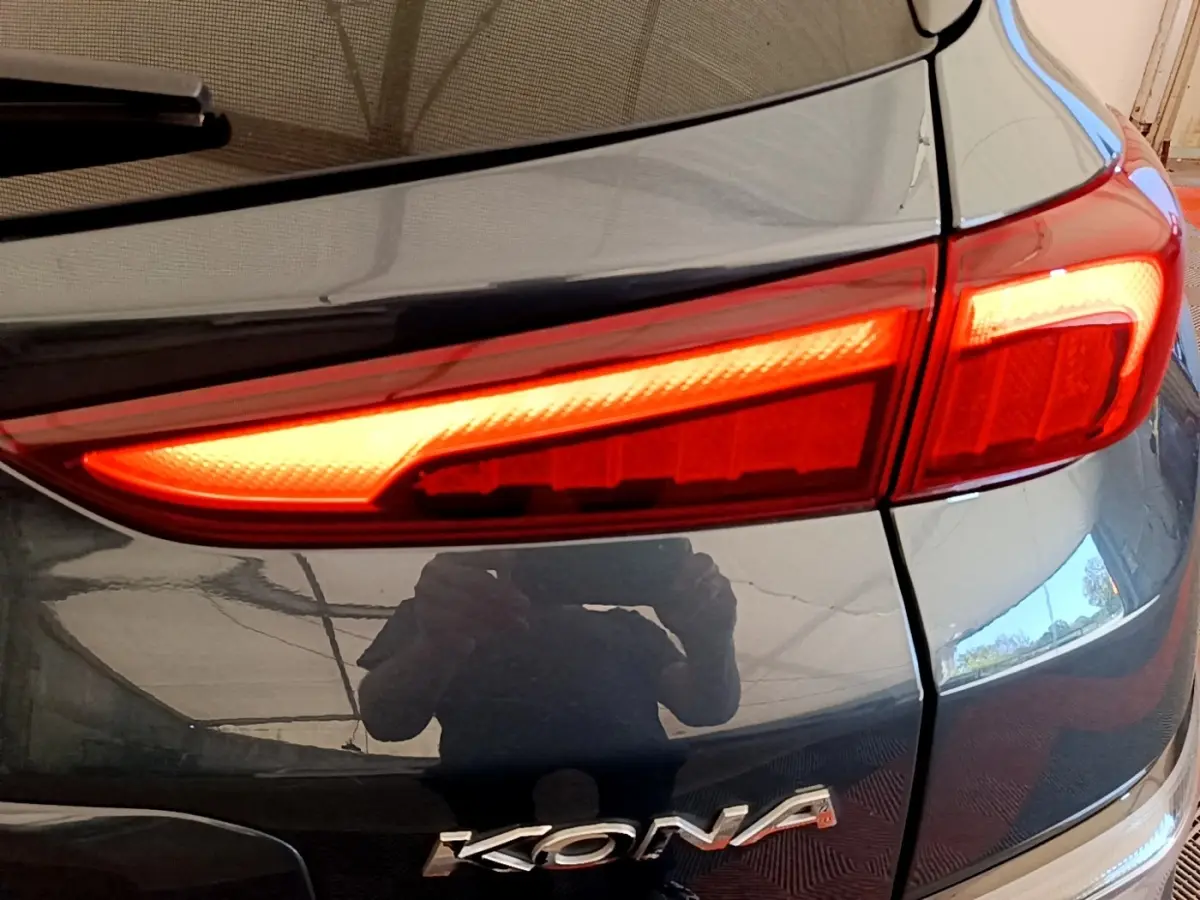 Gros plan sur le feu arrière droit rouge et la carrosserie bleue brillante d’un Hyundai Kona électrique 2023.