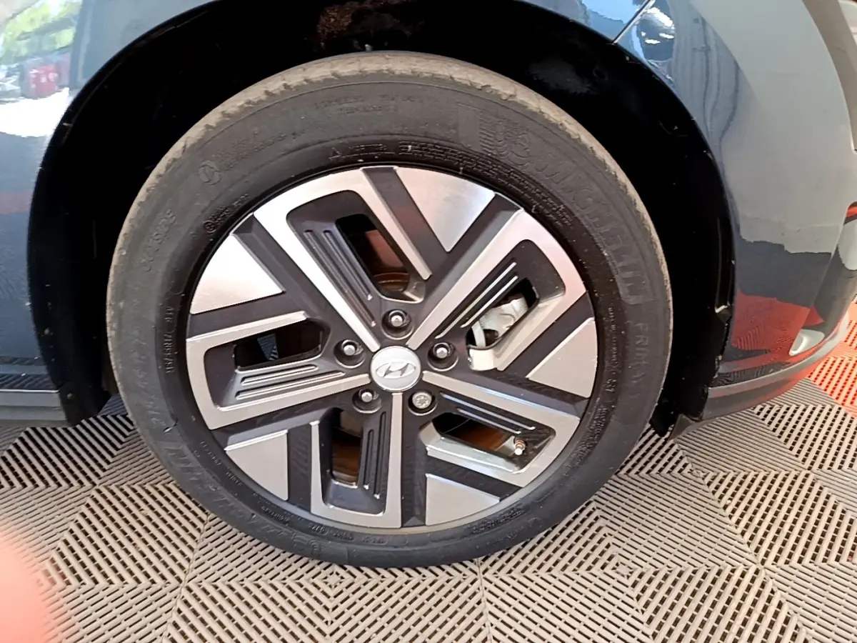 Gros plan sur la roue avant droite d’un Hyundai Kona électrique bleu avec jante alliage bicolore moderne.