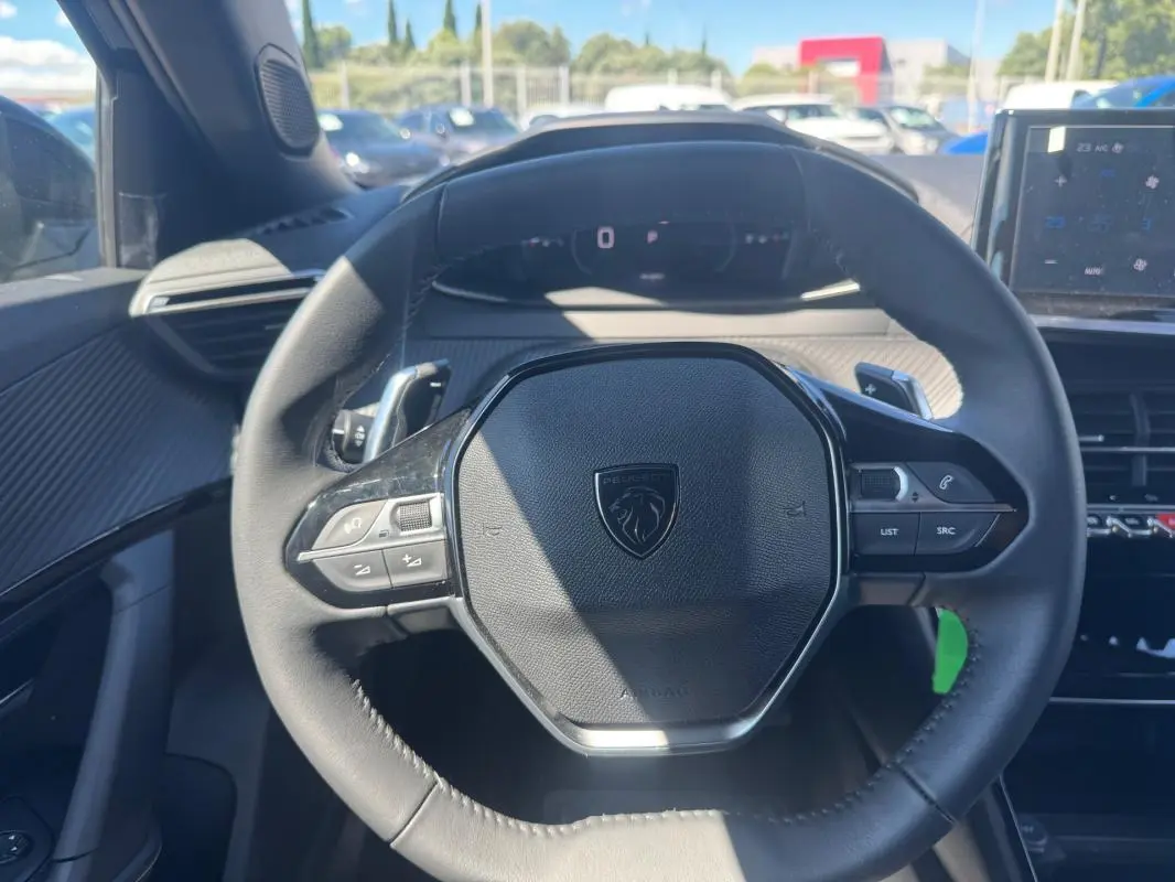 Vue rapprochée du volant noir du Peugeot 2008 Hybrid 136 e-DCS6 Allure 2025 avec commandes intégrées.