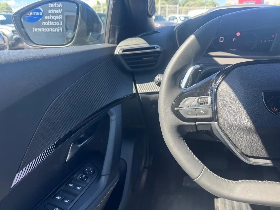 Vue intérieure côté gauche du Peugeot 2008 Hybrid 136 e-DCS6 Allure 2025, volant et panneau de porte noirs avec détails modernes.