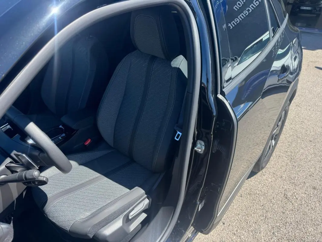 Vue côté gauche intérieur du siège avant d’une Peugeot 2008 Hybrid 136 Allure noir avec porte ouverte au soleil.