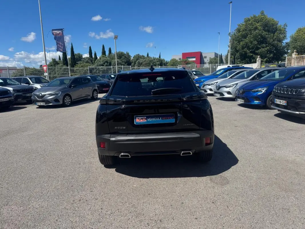 Vue arrière d'un Peugeot 2008 noir 2025 Hybrid 136 e-DCS6 Allure avec double sortie d'échappement et vitres teintées.