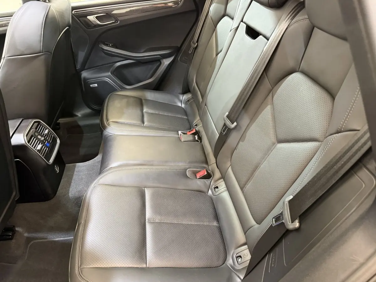 Vue intérieure côté droit des sièges arrière en cuir gris foncé du Porsche Macan 3.0 S avec aérations et ceintures visibles.