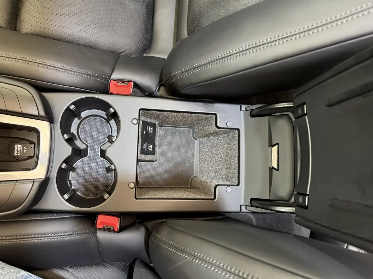 Vue plongeante sur la console centrale noire du Porsche Macan 3.0 S 2019 avec porte-gobelets et rangement ouvert.