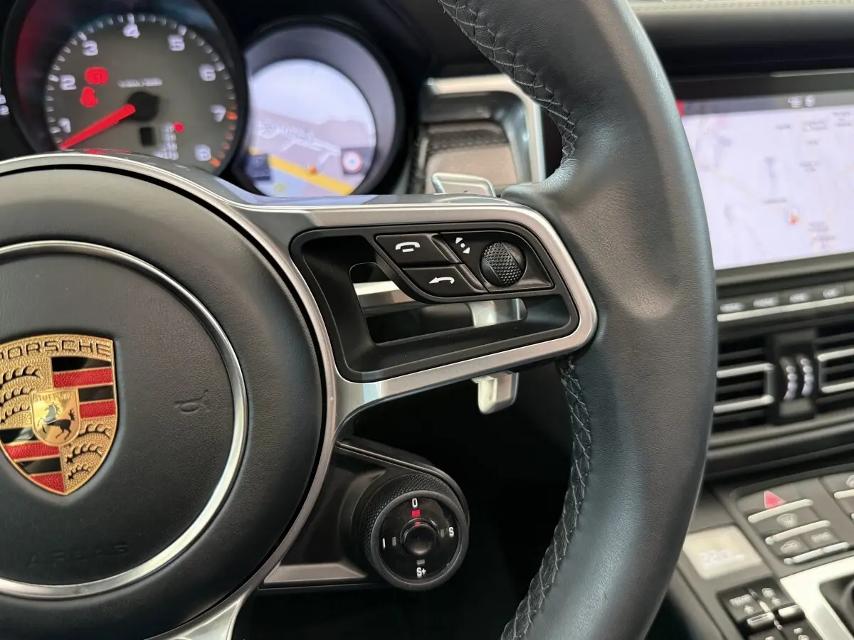 Gros plan sur le volant cuir et alu du Porsche Macan 3.0 S 2019 avec commandes multifonctions et tableau de bord numérique.