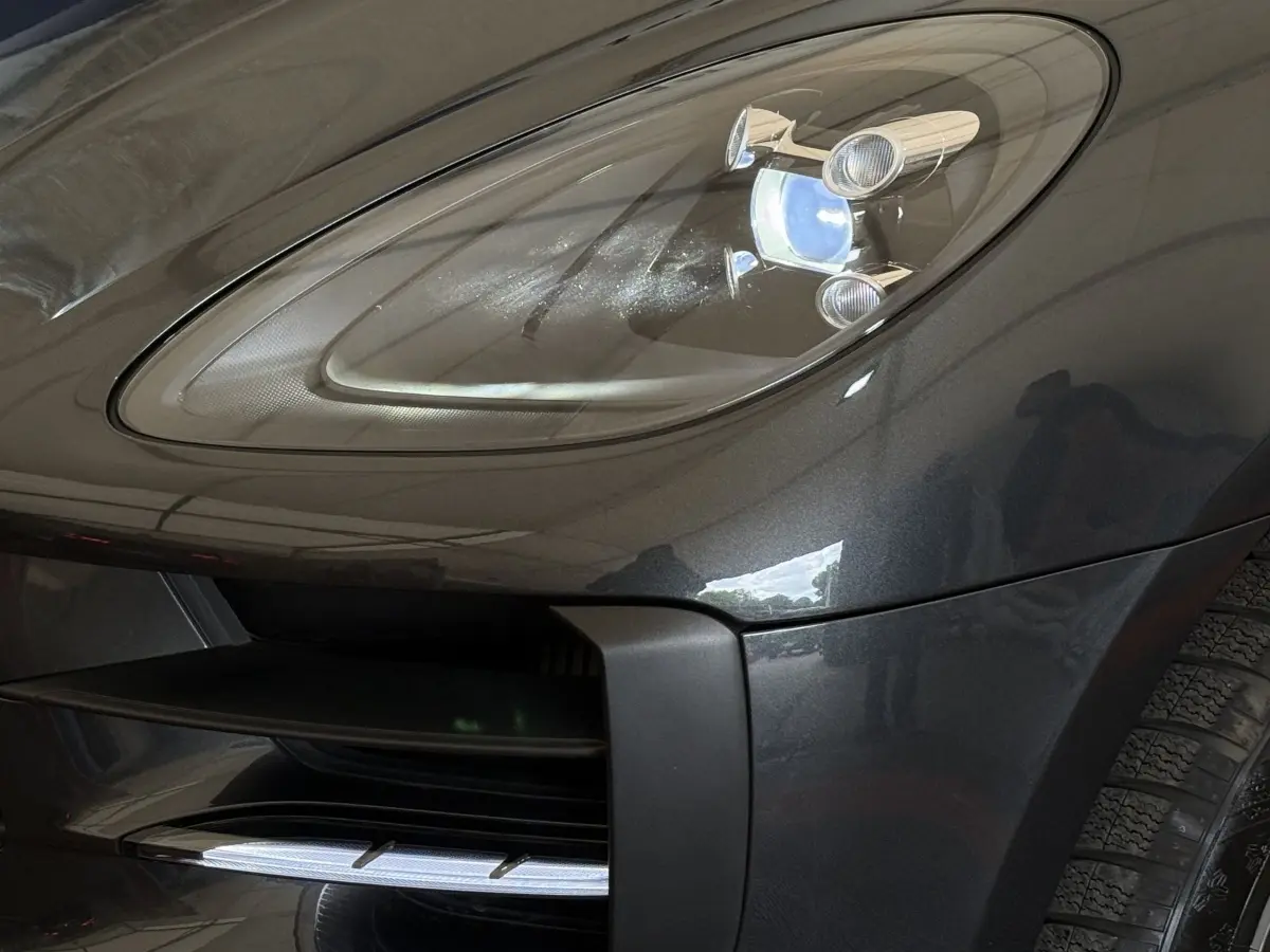 Gros plan sur le phare avant droit du Porsche Macan 3.0 S gris foncé, mettant en valeur le design LED et la calandre.