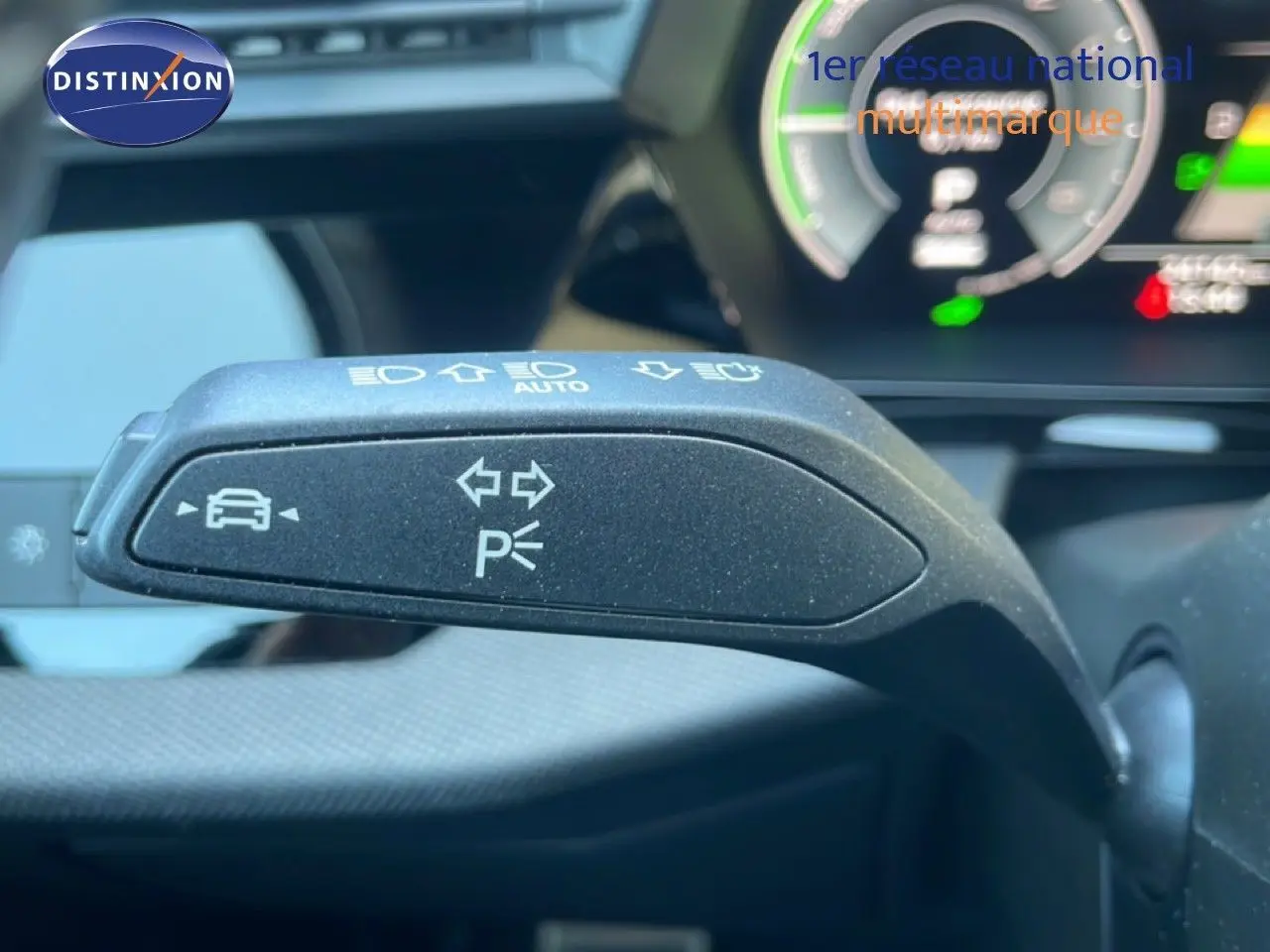 Gros plan sur le commodo de clignotant noir à l'intérieur de l'Audi A3 Sportback 2025, avec tableau de bord numérique en arrière-plan.
