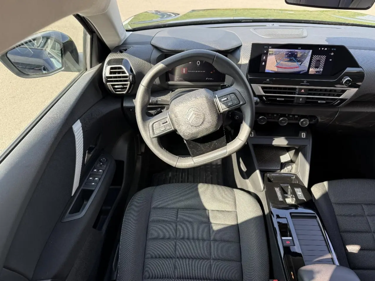Vue intérieure de face du poste de conduite du Citroën C4 2025, avec volant multifonction et écran tactile central.