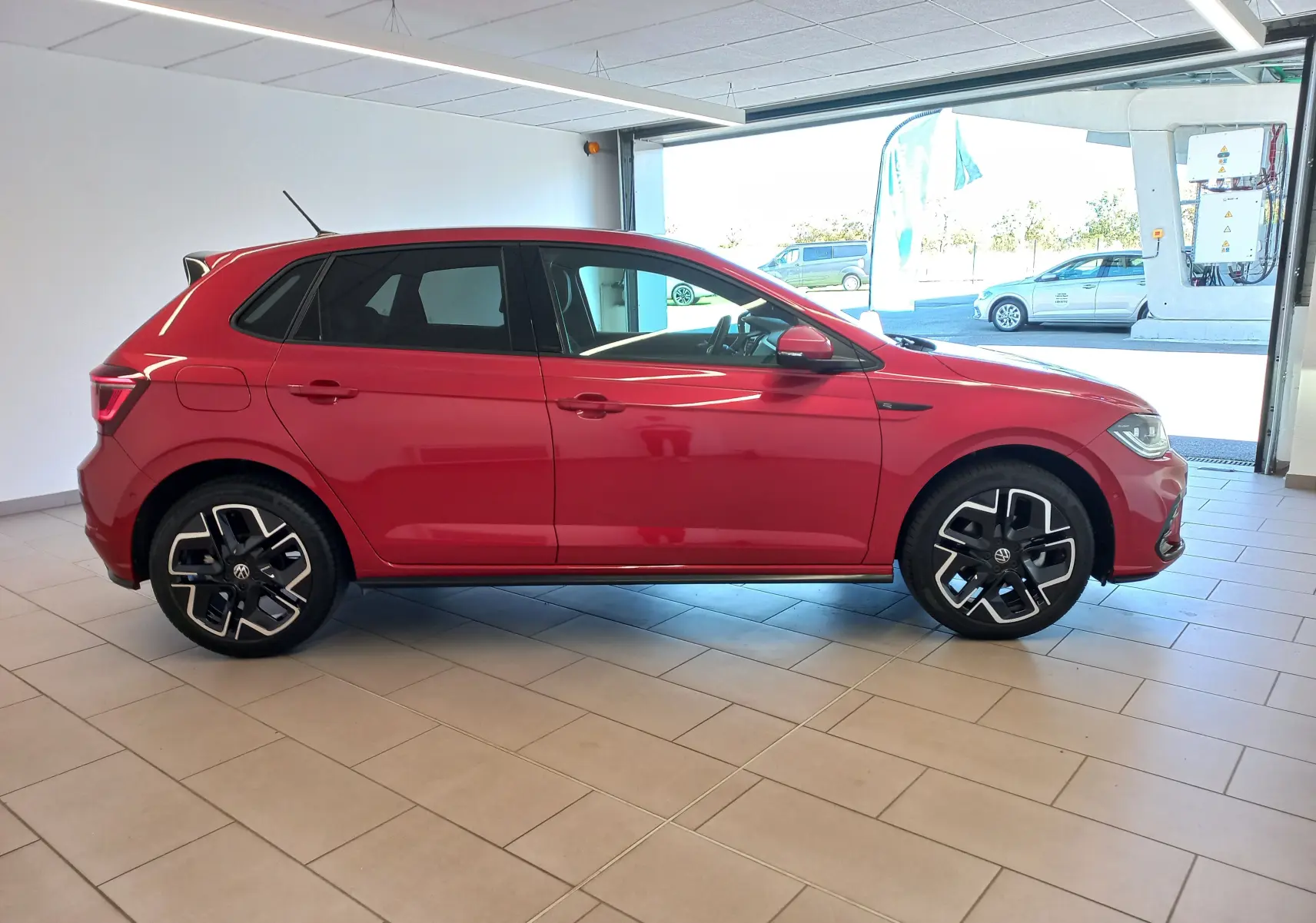 Volkswagen Polo 1.0 TSI 116 DSG7 R-Line Edition rouge roi vue de profil côté gauche en intérieur, jantes noires distinctives.