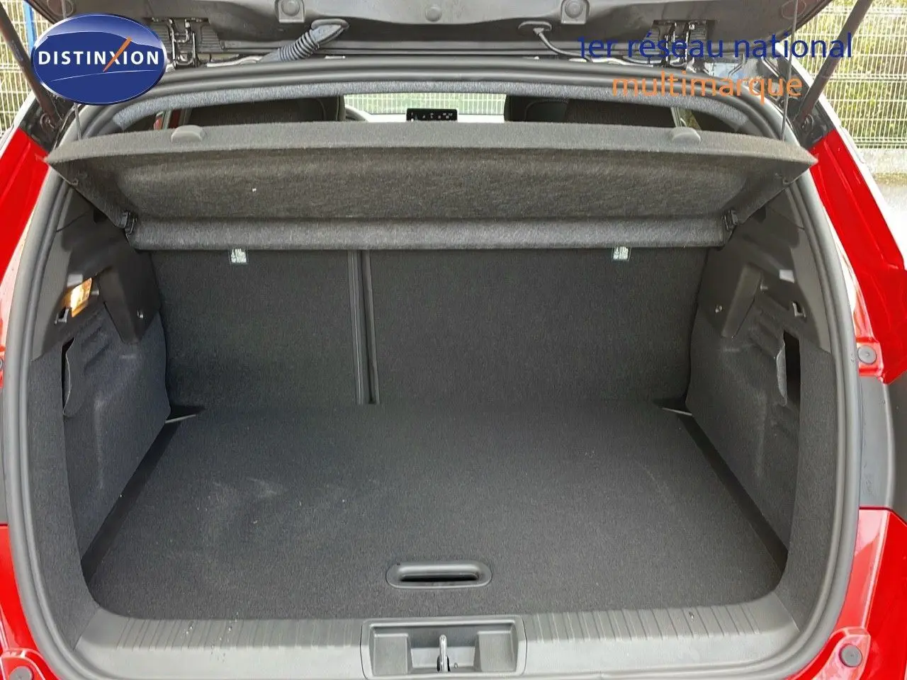 Coffre ouvert d'un Renault Captur rouge passion 2025, montrant un espace de chargement vide et bien agencé.
