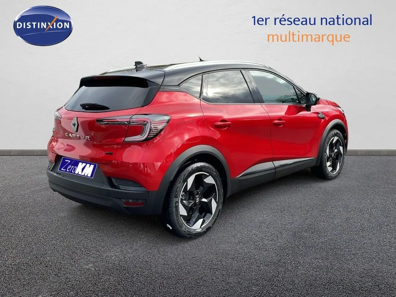 Vue 3/4 arrière droite du Renault Captur E-Tech hybride rouge passion avec toit noir et jantes bicolores.