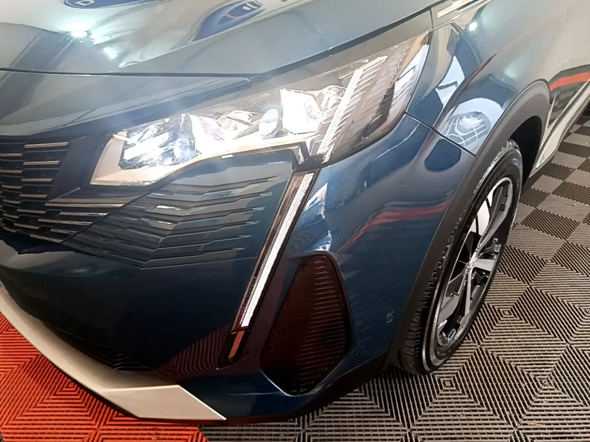 Gros plan sur l'avant droit bleu du Peugeot 5008 2021, mettant en valeur le phare LED et la calandre distinctive.