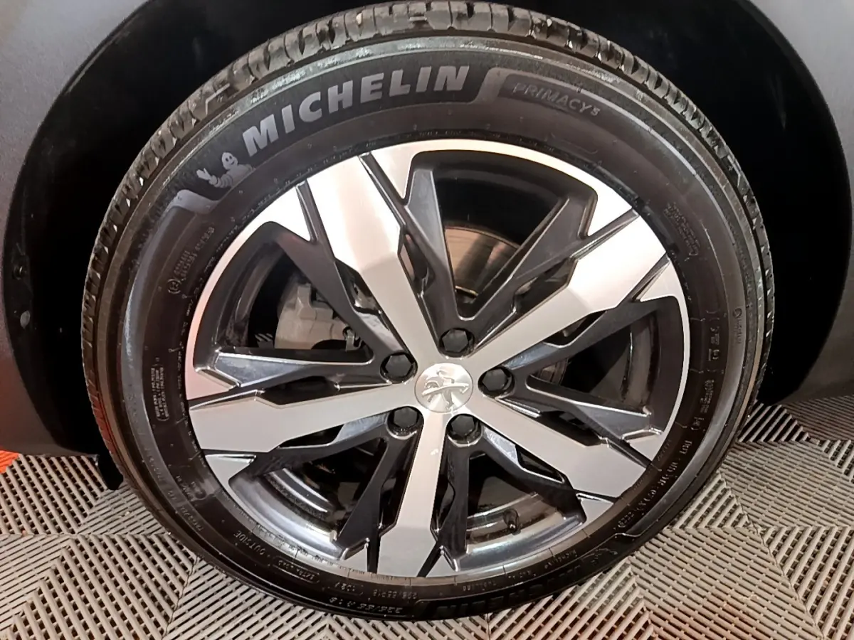 Gros plan sur la jante alliage bicolore et pneu Michelin d'un Peugeot 5008 bleu, côté gauche.