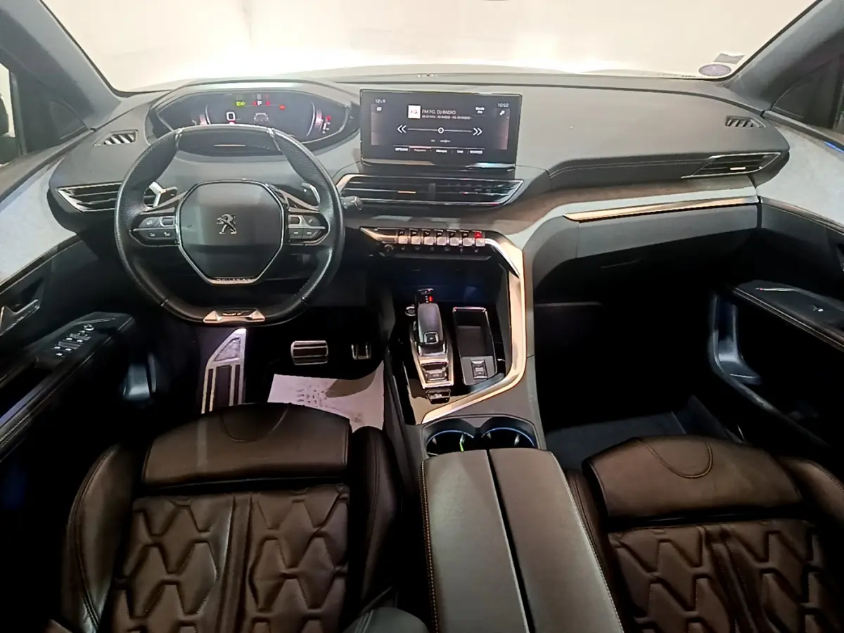 Intérieur Peugeot 5008 GT vu de face, tableau de bord moderne avec écran tactile et volant cuir noir.