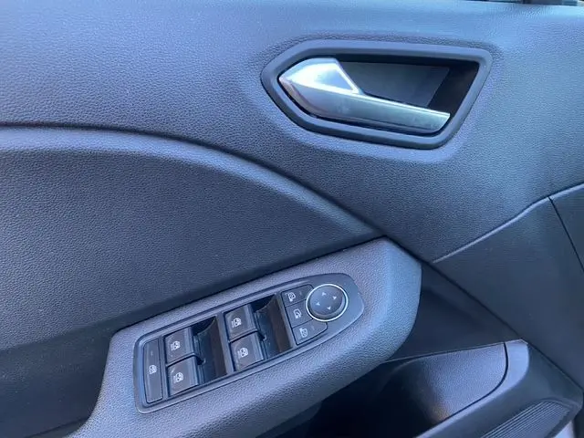 Gros plan sur la porte côté conducteur de la Renault Clio V gris schiste, avec commandes des vitres et poignée argentée.