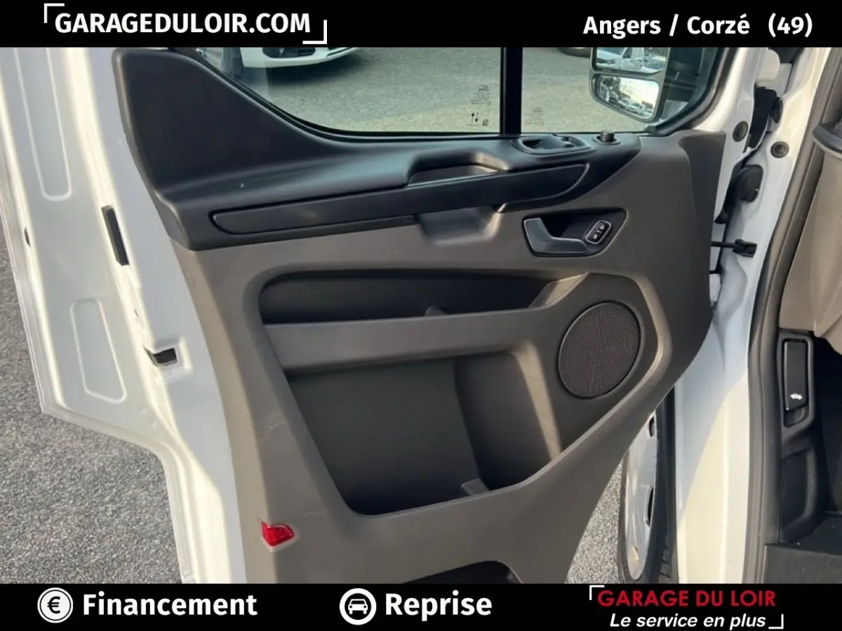 Vue rapprochée de la porte avant gauche blanche du Ford Transit Custom avec panneau intérieur noir et haut-parleur intégré.