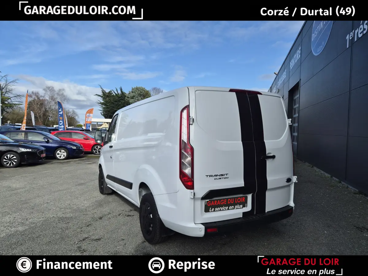Vue 3/4 arrière droite du Ford Transit Custom blanc avec bande noire verticale centrale sur les portes arrière.
