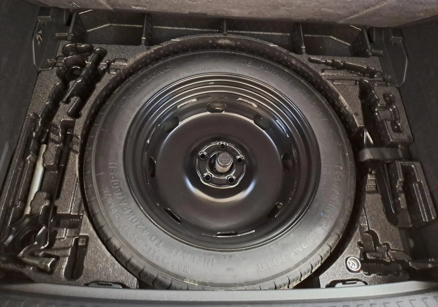 Gros plan sur la roue de secours compacte 18'' noire dans le coffre du CUPRA TERRAMAR 2025, version essence bleu Fjord.