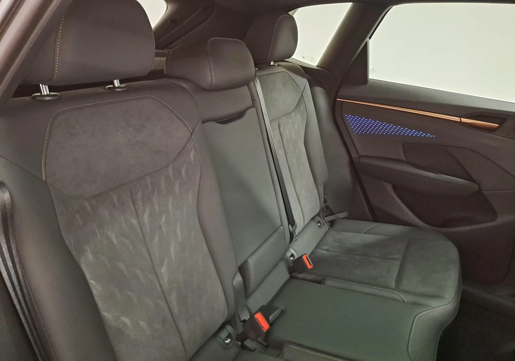 Vue intérieure côté droit des sièges arrière en tissu et cuir noir avec éclairage d'ambiance bleu sur la porte du CUPRA TERRAMAR.