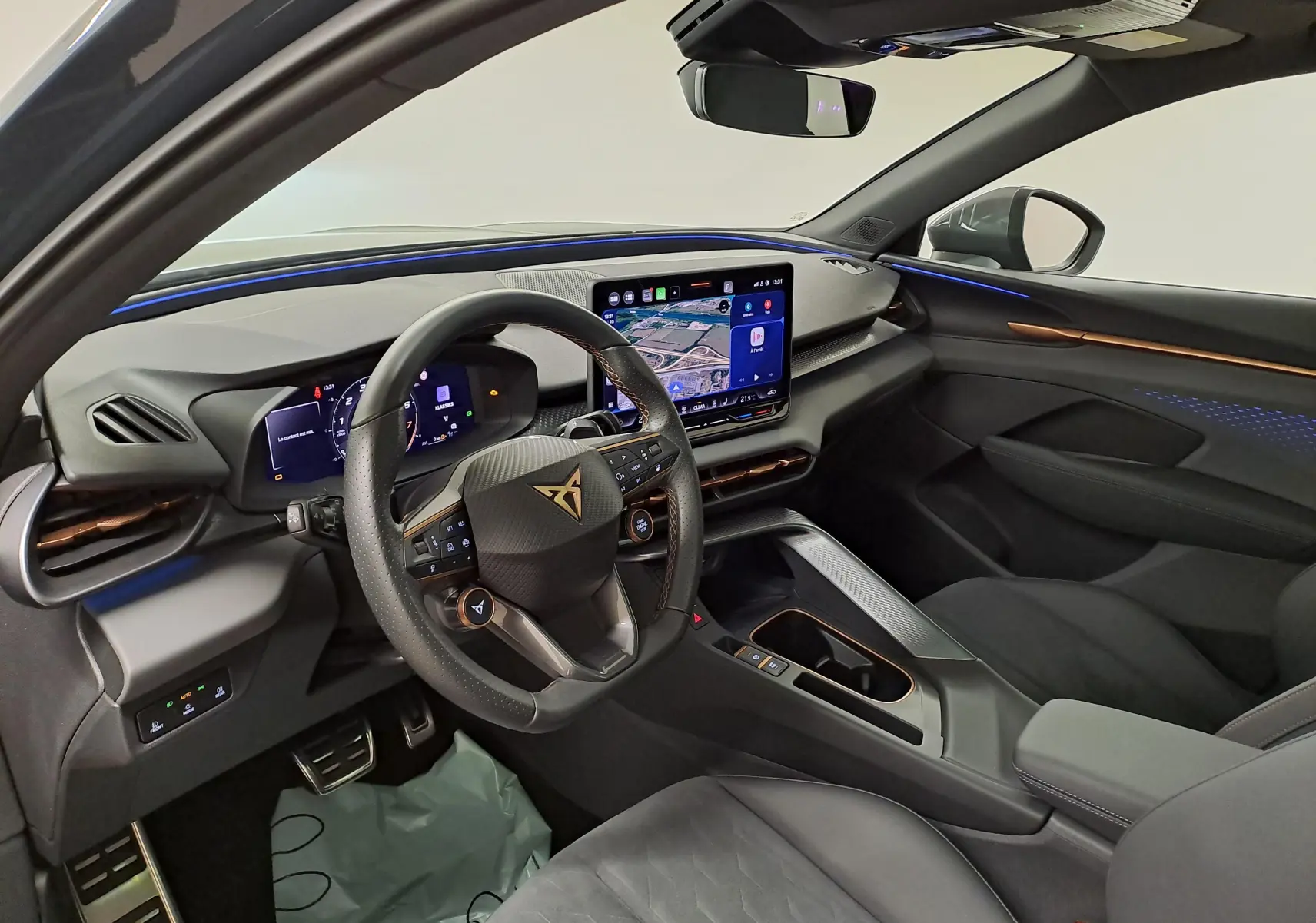 Vue intérieure côté conducteur du CUPRA TERRAMAR 2025, tableau de bord moderne avec écran tactile et éclairage d'ambiance bleu.