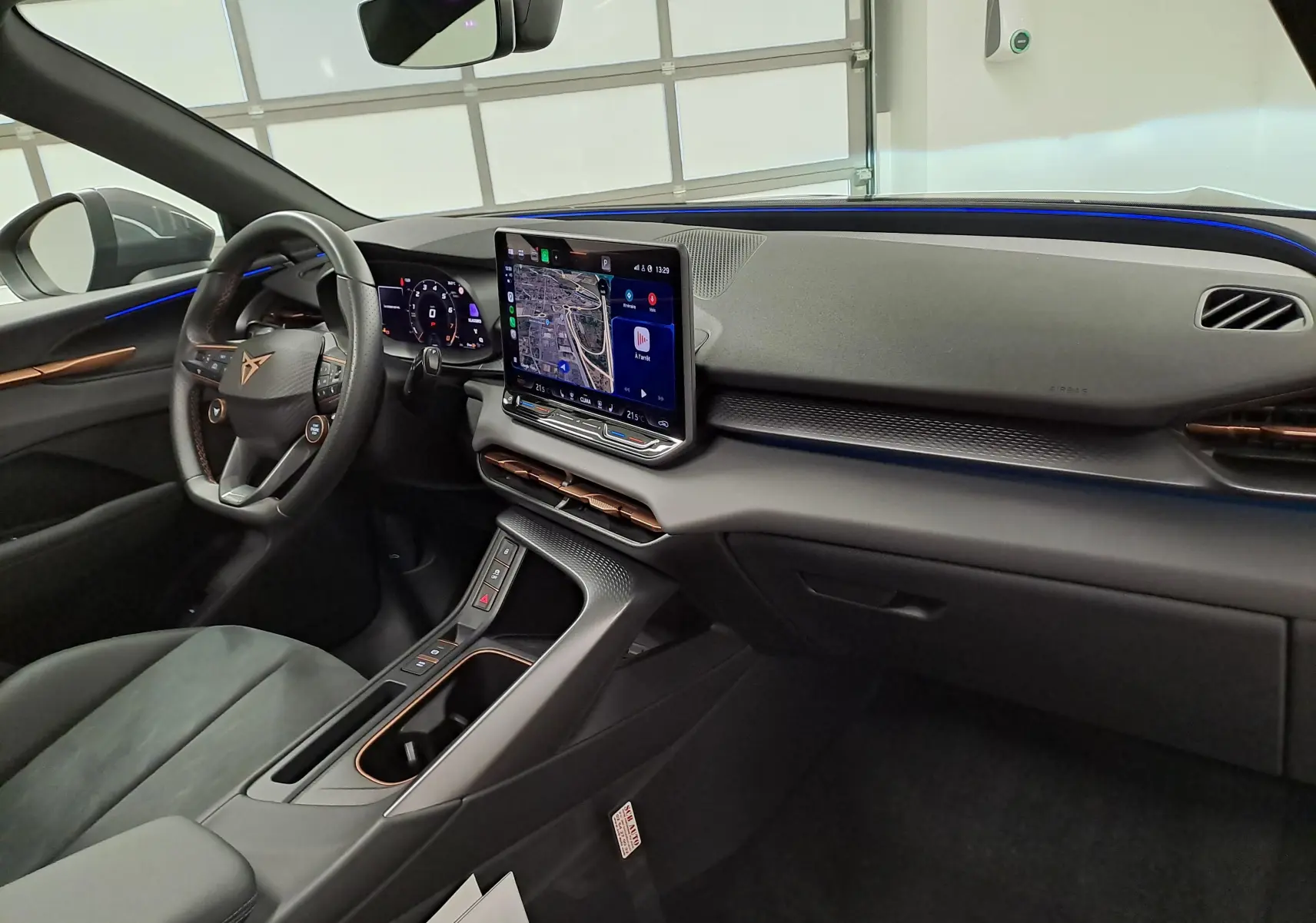 Vue intérieure côté conducteur du tableau de bord du CUPRA TERRAMAR 2025 avec écran tactile et éclairage d'ambiance bleu.