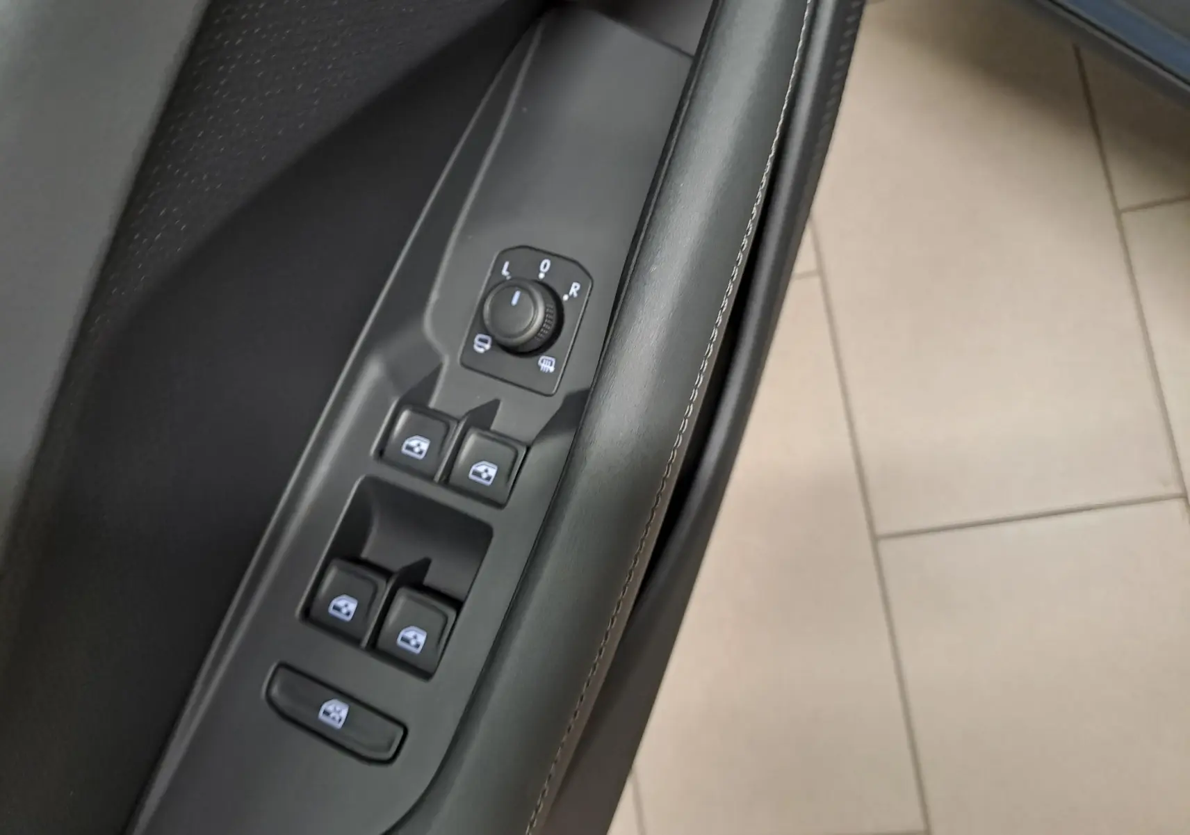 Gros plan sur les commandes de lève-vitres et réglage des rétroviseurs côté conducteur du CUPRA TERRAMAR 2025.