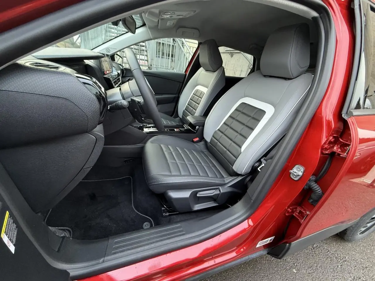 Vue intérieure côté conducteur du Citroën C4 rouge elixir 2025, avec sièges bi-ton gris et noir en cuir.
