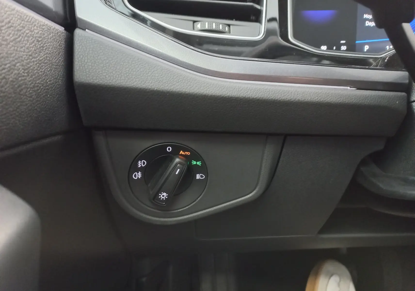 Gros plan sur le bouton de commande des phares à gauche du tableau de bord d'une Volkswagen Polo 2026.