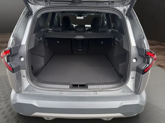 Vue arrière du coffre ouvert d’un Dacia Bigster gris foncé, montrant un espace de chargement spacieux et la banquette arrière rabattable.
