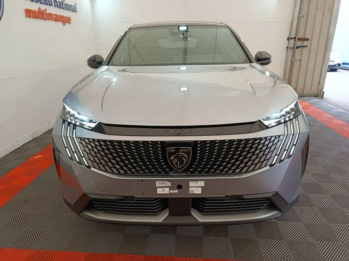 Vue frontale du Peugeot 3008 gris clair 2025 avec calandre distinctive et feux LED verticaux allumés