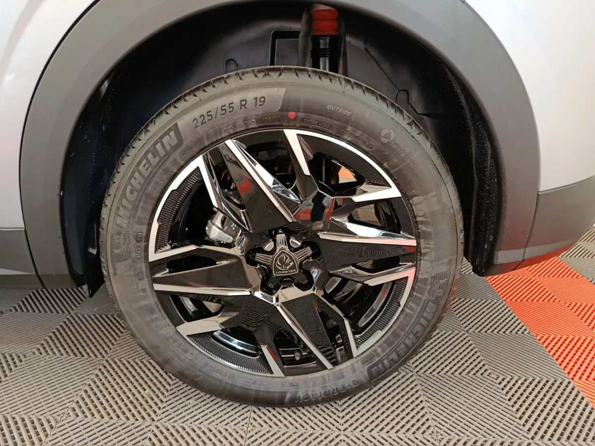 Gros plan sur la roue avant droite du Peugeot 3008 gris clair, jante alliage noire et chromée, pneu Michelin 19 pouces.