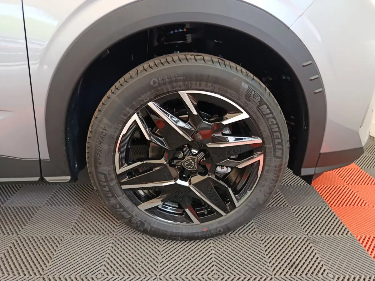Gros plan sur la roue avant gauche du Peugeot 3008 gris clair avec jante alliage noire et chromée.