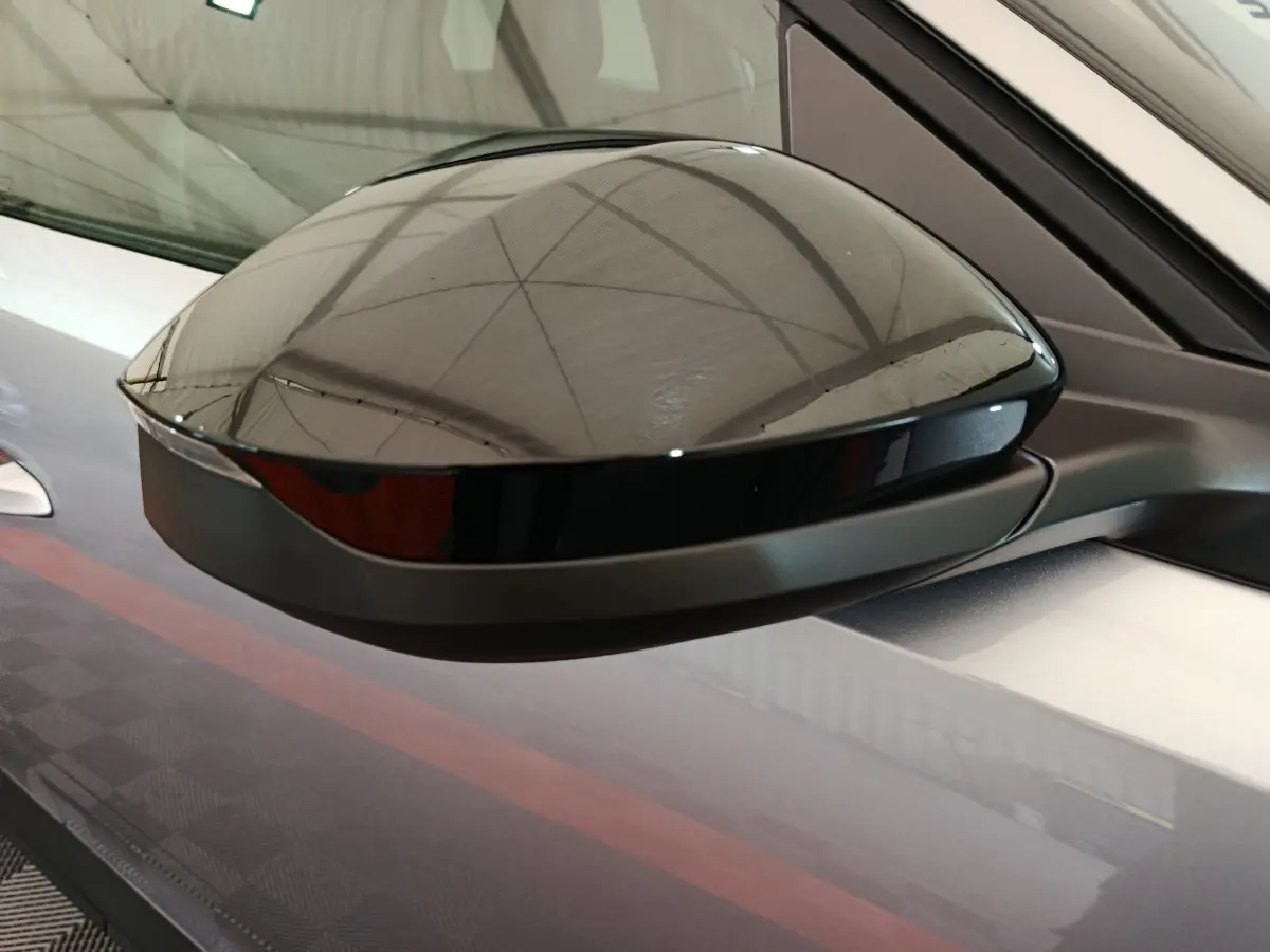 Gros plan sur le rétroviseur côté gauche noir brillant du Peugeot 3008 gris clair hybride 2025.