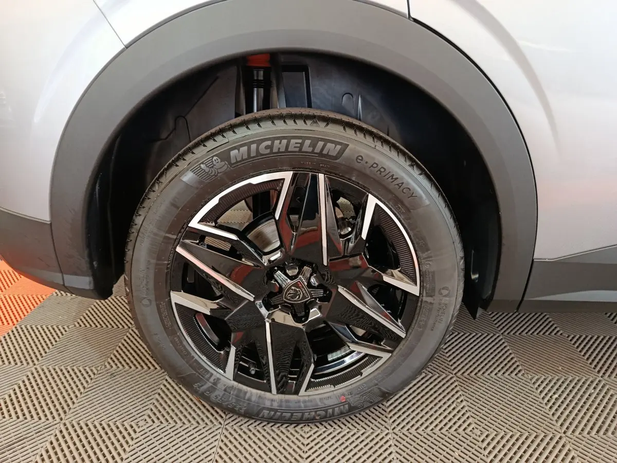 Gros plan sur la roue avant droite du Peugeot 3008 gris clair avec jante noire et détails argentés Michelin e-Primacy.