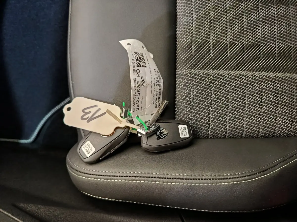 Clé de voiture Peugeot posée sur un siège avant en cuir noir avec coutures blanches, intérieur du 3008 hybride 2025.