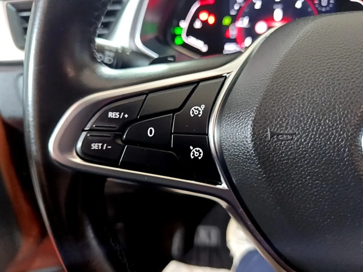 Gros plan sur les commandes de régulateur de vitesse au volant cuir noir du Renault Captur jaune, version Intens 2020.