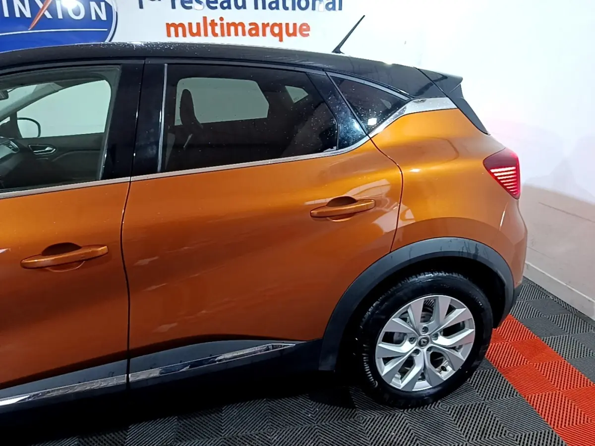 Vue latérale droite du Renault Captur Intens jaune avec toit noir et jantes alliage visibles sur fond intérieur.