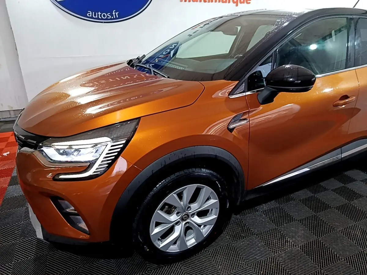 Vue 3/4 avant droit d'un Renault Captur orange métallisé avec phares LED et rétroviseurs noirs.