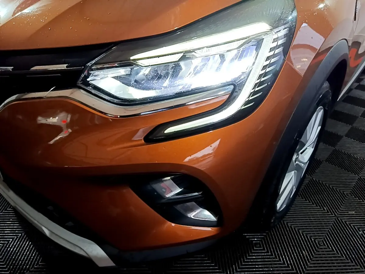 Gros plan sur l'avant droit du Renault Captur jaune, mettant en valeur le phare LED et la calandre chromée.